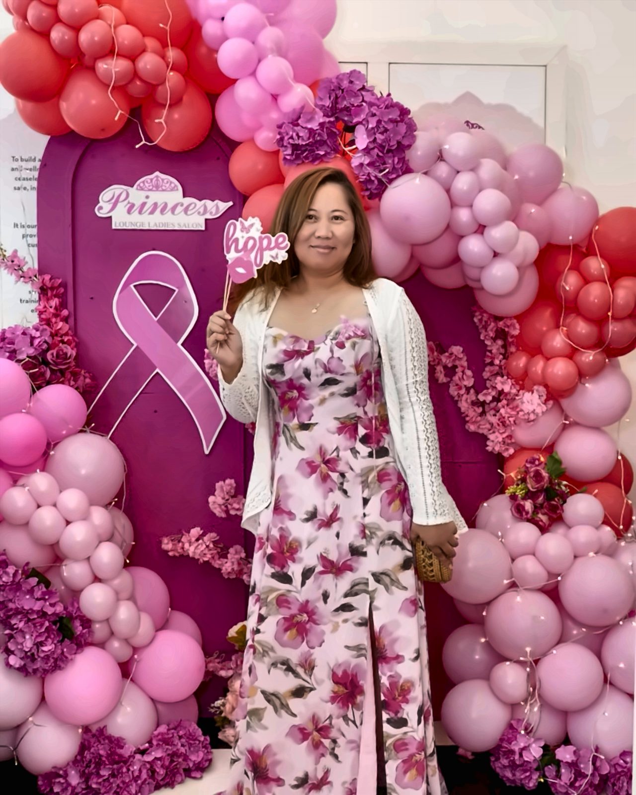 Woman in a floral gown at a pink-themed Princess Lounge Ladies Salon brand event with balloon decor