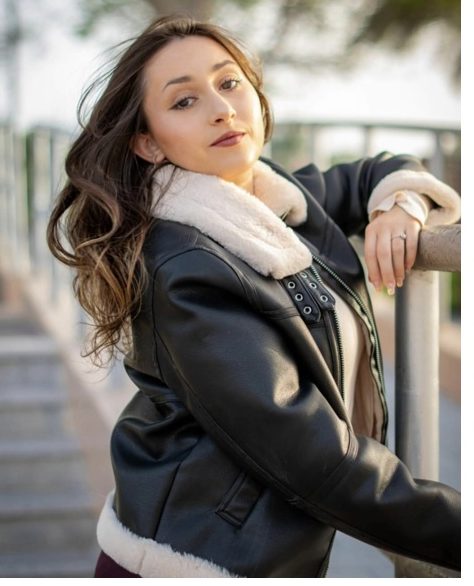 Outdoor portrait of a woman in a shearling leather jacket leaning on a railing